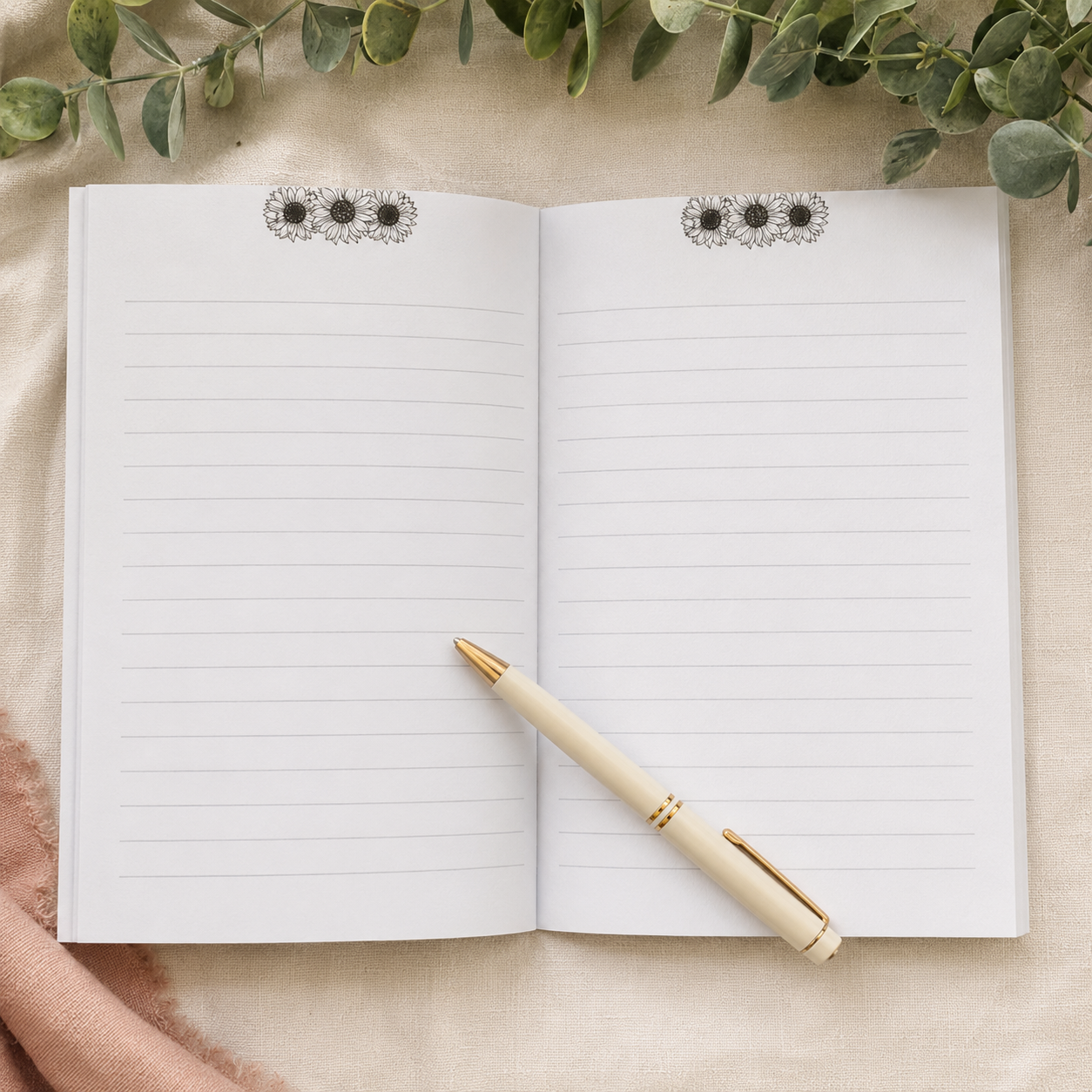 An open lined notebook with three black-and-white floral page headers, styled on a beige fabric surface with eucalyptus leaves and a cream pen with gold trim.