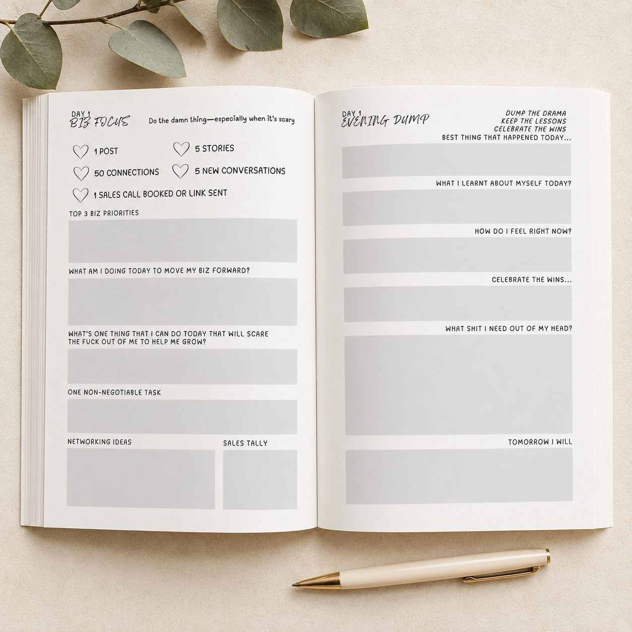An open planner or notebook spread on a light beige surface, showing two white pages with handwritten and printed productivity/planning sections. A gold pen rests at the bottom, and green leaves are partially visible at the top edge.