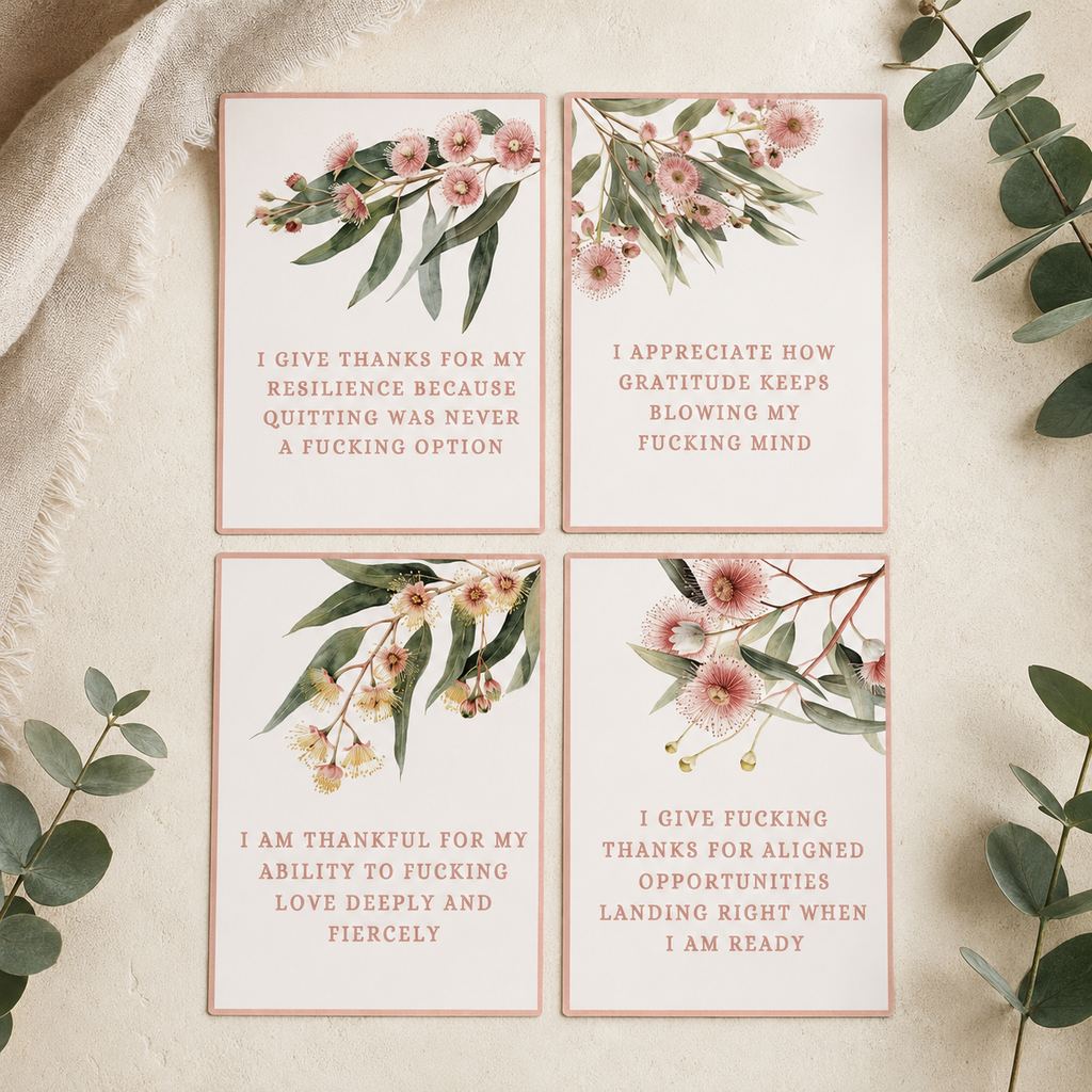 Four rectangular printed cards with floral illustrations and short text are arranged in a 2x2 grid on a light textured surface with greenery and fabric around them. The cards appear to be the product being sold.