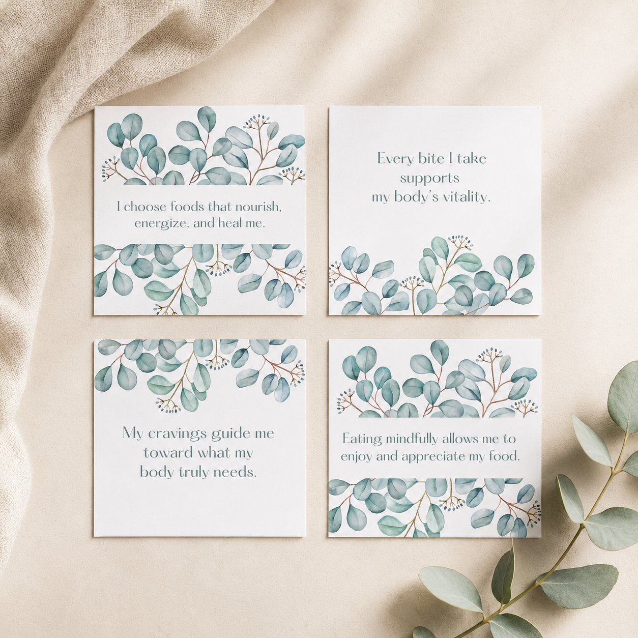 Four square white cards with watercolor eucalyptus leaf borders and short inspirational quotes, arranged in a 2x2 grid on a beige fabric surface with eucalyptus leaves around them.
