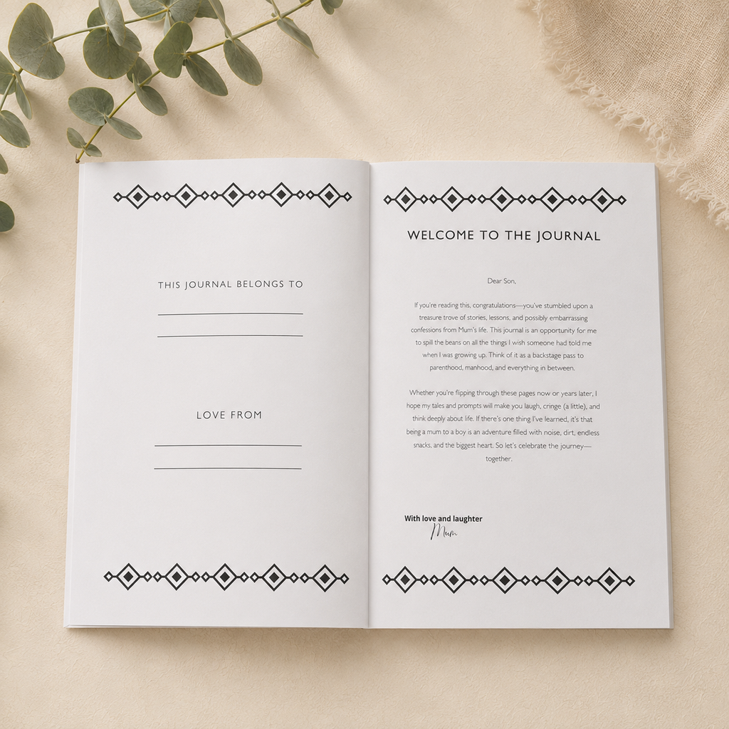 An open white journal spread laid flat on a light beige textured surface with eucalyptus leaves in the corner. The pages feature black geometric border designs at the top and bottom and printed text including 'WELCOME TO THE JOURNAL' and fill-in lines.