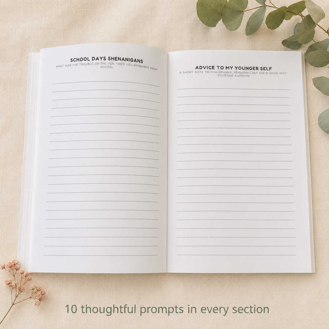 An open lined journal laid flat on a light beige fabric background, with printed prompts at the top of both pages and decorative eucalyptus leaves and dried flowers around it. Text at the bottom reads, '10 thoughtful prompts in every section.