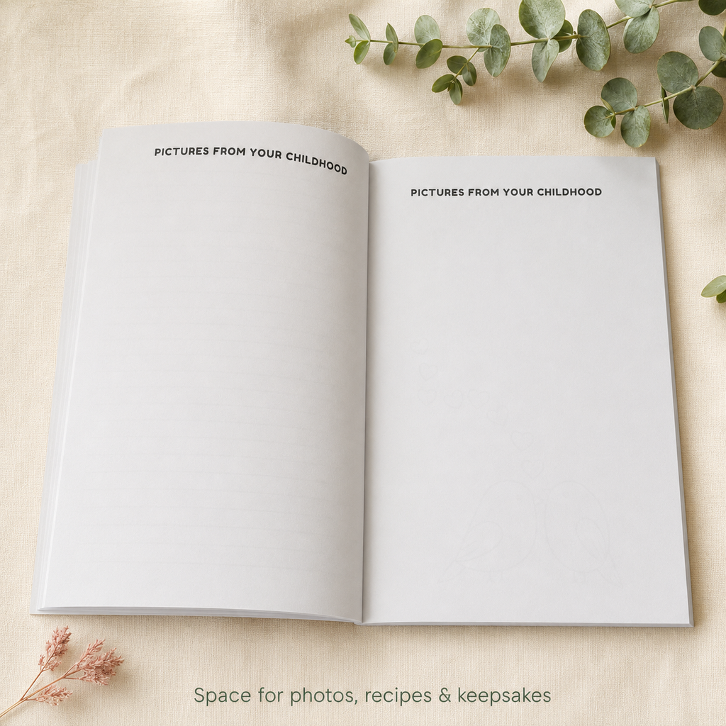 An open white keepsake album or photo book laid flat on a light beige fabric surface, with the title printed at the top of both pages: 'PICTURES FROM YOUR CHILDHOOD.' Decorative eucalyptus stems and small dried flowers surround it, and faint text at the bottom reads 'Space for photos, recipes & keepsakes.